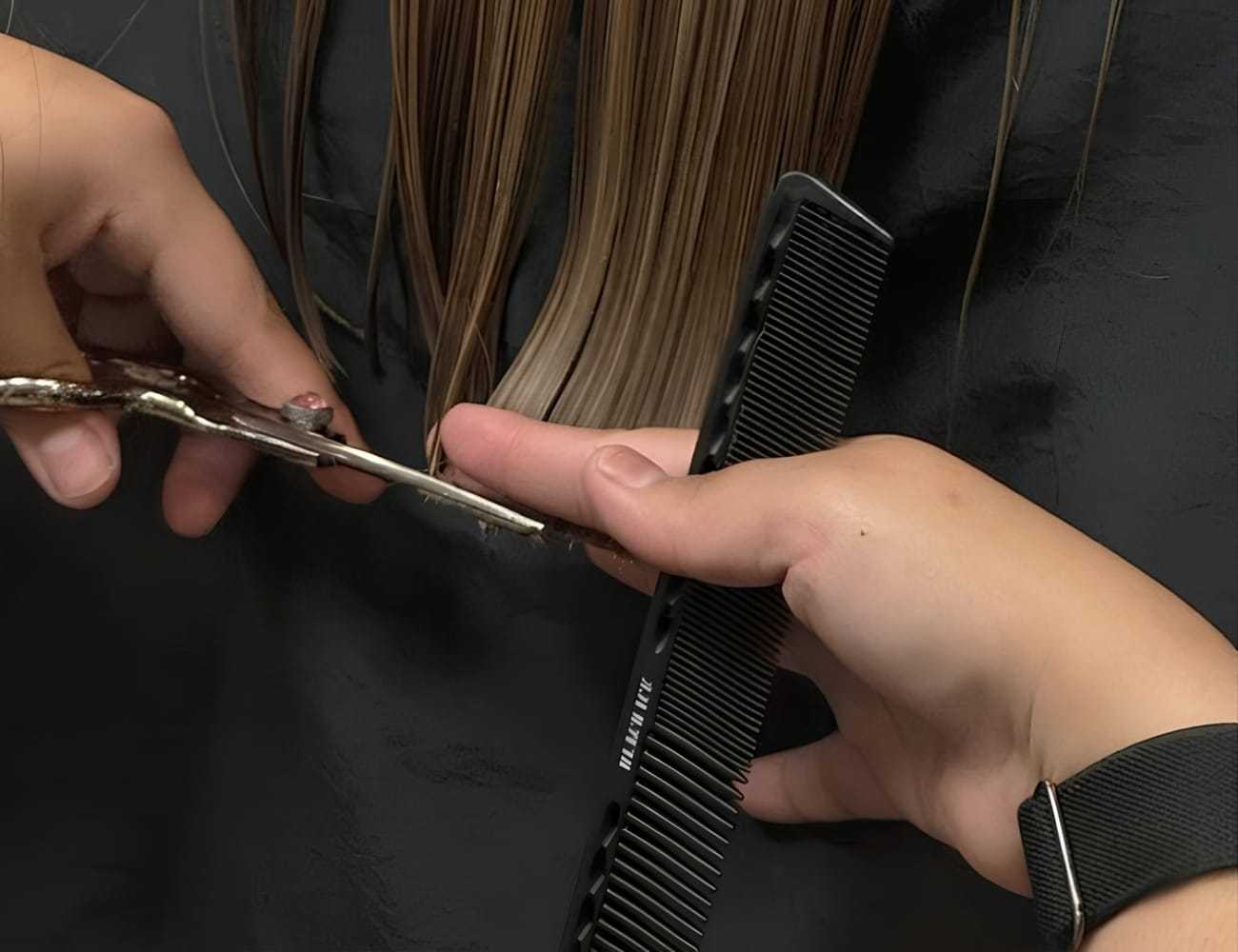 Hair being cut with scissors and comb in a salon setting.