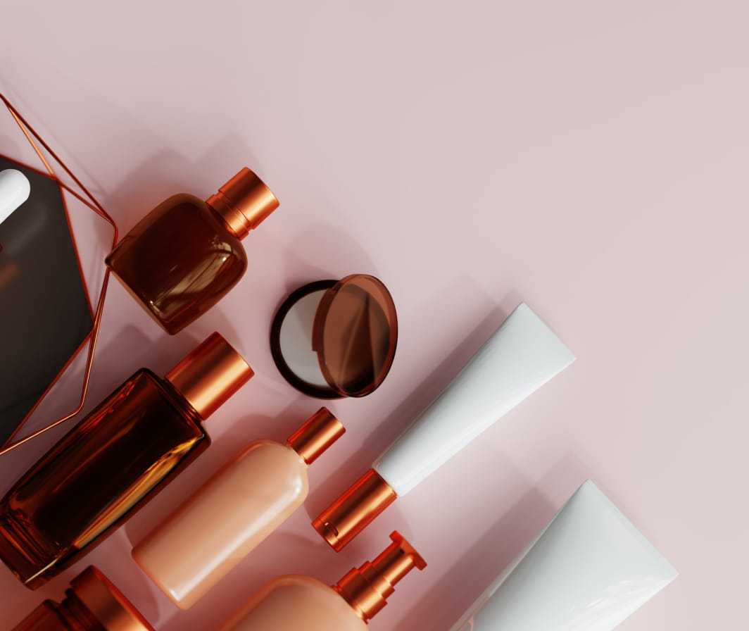 Beauty product bottles and containers arranged on a pink background.